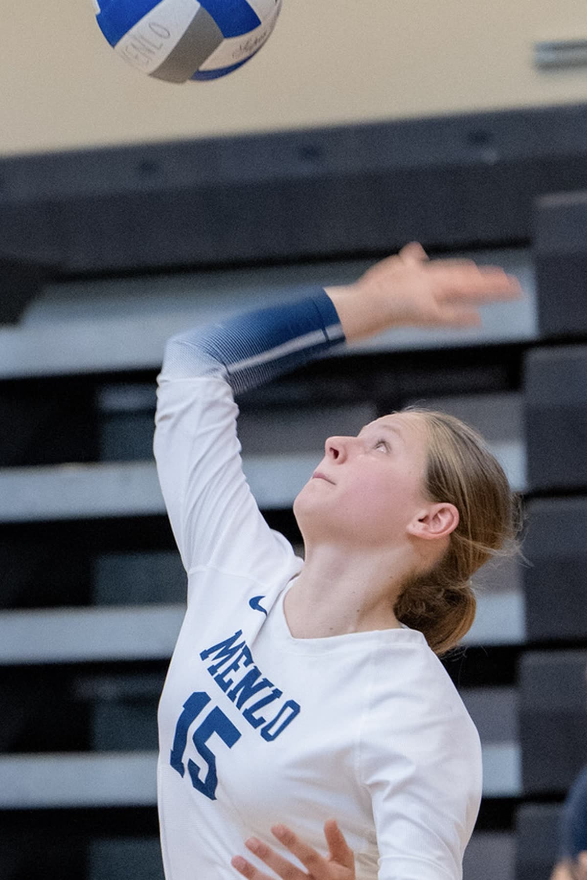 Young volleyball player serving on an indoor court
